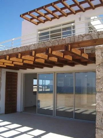 Shaded outdoor space beneath a slatted overhead structure.