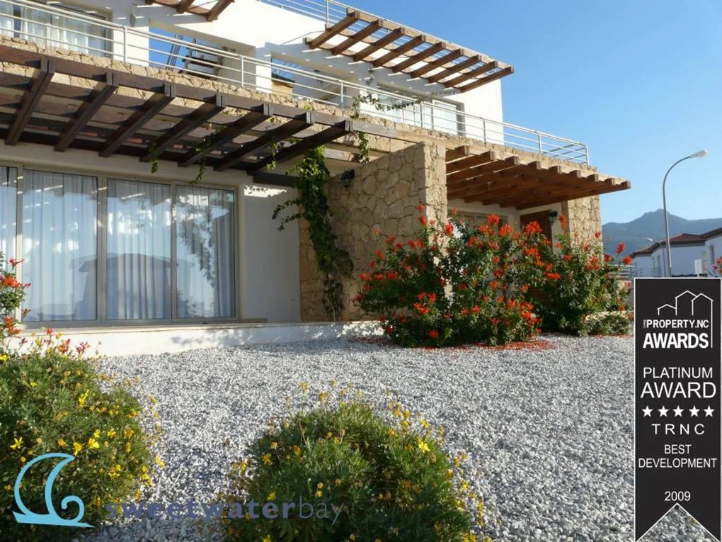 Shaded outdoor space beneath a slatted overhead structure.