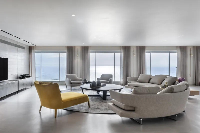 Living room with seating, tables and large windows.