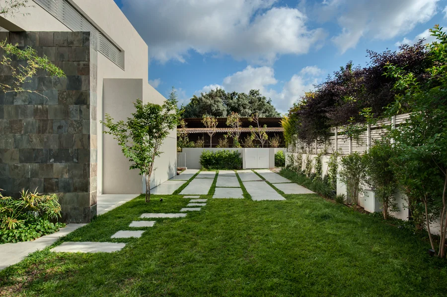 House and glazed living space opening onto a planted lawn.